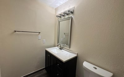 Updated half bathroom featuring contemporary fixtures, a sleek vanity, upgraded lighting, and attractive flooring. This refreshed space adds convenience and modern appeal to the home.