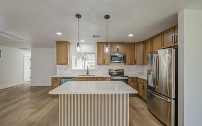 Gather around the oversized island in this beautifully remodeled kitchen featuring elegant white oak cabinetry, quartz countertops, stainless steel appliances, and stylish pendant lighting.
