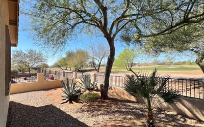 Backyard overlooking the fairway with mature desert trees, attractive landscaping, decorative stone accents, and scenic mountain views. This premium outdoor setting offers both privacy and breathtaking natural surroundings.