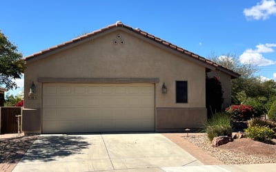 Charming front exterior with mature desert landscaping, spacious driveway, two-car garage, and attractive paver accents creating beautiful curb appeal in a desirable Buckeye neighborhood.