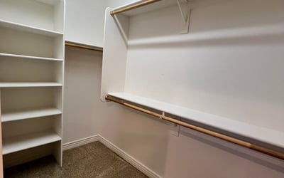 Large walk-in closet complete with built-in shelving, multiple hanging sections, and spacious storage designed to keep clothing and accessories neatly organized.
