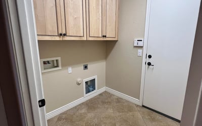 Dedicated laundry room with custom cabinetry, tile flooring, utility hookups, and extra storage space for household essentials, adding convenience to everyday living.