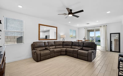 The expansive great room offers an open layout with durable wood-look flooring, recessed lighting, ceiling fan, and flexible space for relaxing, entertaining, and everyday living.