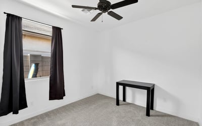 A welcoming secondary bedroom featuring plush carpeting, ceiling fan, natural light, and flexible space for guests, family members, or everyday living.