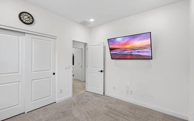 This comfortable secondary bedroom offers soft carpeting, neutral finishes, recessed lighting, and flexible space suitable for guests, children, or a private office in Surprise.