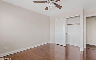 This secondary bedroom features attractive wood flooring, a ceiling fan, ample closet space, and a flexible layout that adapts easily to changing household needs.