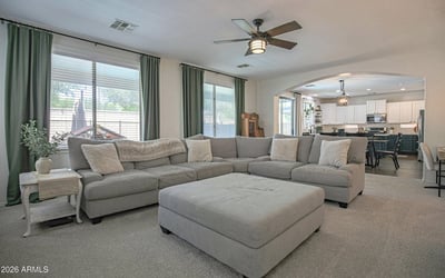 Spacious family room with plush carpeting, oversized windows, and an open layout connecting seamlessly to the kitchen. Perfect for entertaining guests or relaxing with family.