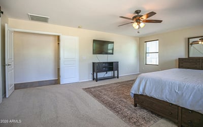 Spacious primary bedroom featuring soft carpeting, a ceiling fan, and an open layout with room for oversized furniture. A comfortable owner's retreat designed for relaxation and everyday living.