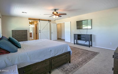 Comfortable primary bedroom with expansive floor space, plush carpeting, entertainment area, and convenient access to the luxurious en-suite bathroom. Designed for everyday comfort in Waddell.