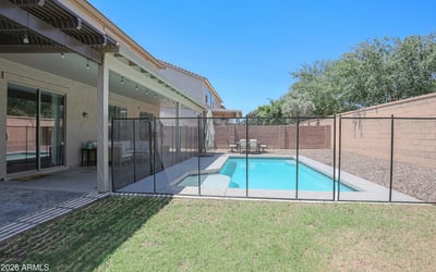 Spacious backyard featuring a fenced pool, covered patio, and open green space ideal for recreation and outdoor enjoyment. A well-designed backyard retreat in desirable Waddell.