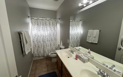 Full bathroom showcasing a spacious dual-sink vanity, large mirror, and tub/shower combination, providing practical convenience for family members and guests.