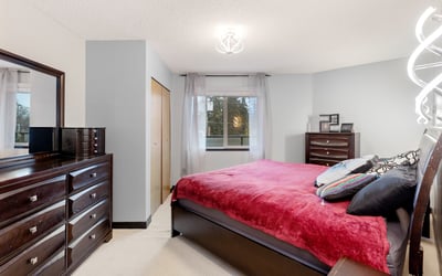 This inviting bedroom features modern decor, ample storage, and large windows for natural light.