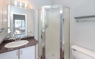 Modern bathroom featuring a glass shower, sleek countertops, and ample storage for convenience and functionality.