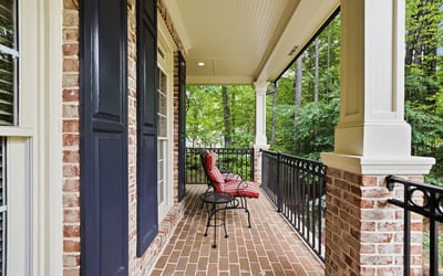 Inviting porch space with brick flooring and views of lush greenery, perfect for outdoor relaxation.