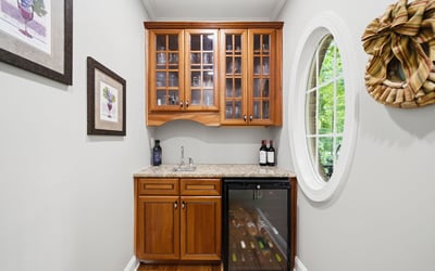Perfect for entertaining, this cozy wine nook features stylish cabinetry and a compact fridge for easy access.