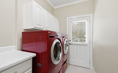 Bright and functional laundry room featuring modern red appliances and ample storage space.