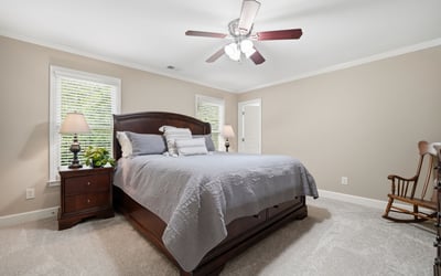 Spacious bedroom featuring natural light, a ceiling fan, and ample room for relaxation and comfort.