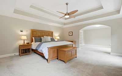 Spacious master bedroom with tray ceiling, abundant natural light, and an adjoining versatile living area.