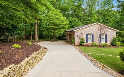 Discover a welcoming home nestled among lush greenery, featuring a spacious driveway and inviting outdoor spaces.