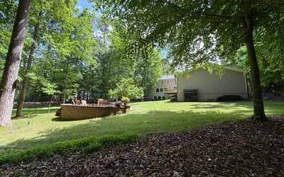 Spacious backyard surrounded by trees, perfect for outdoor gatherings and relaxation in a peaceful setting.