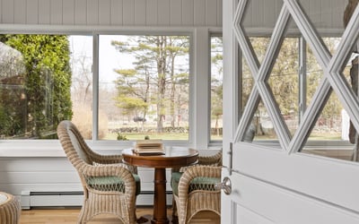 Inviting sunlit space featuring expansive windows and cozy seating, perfect for relaxation and gatherings.