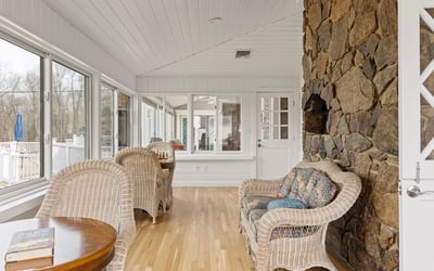 Light-filled sunroom featuring a stone wall, perfect for relaxation or entertaining with expansive views.