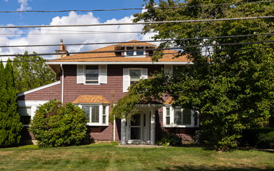Spacious home featuring a well-maintained lawn, mature trees, and a welcoming entrance, perfect for family living.