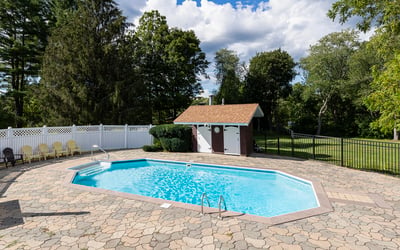 Inviting outdoor space features a spacious pool surrounded by lush greenery and a convenient shed for storage.