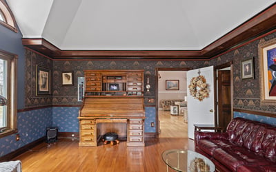Spacious living area featuring distinctive woodwork, a classic desk, and inviting natural light throughout.