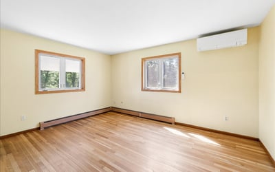 Bright and open room featuring hardwood floors and natural light from two large windows.