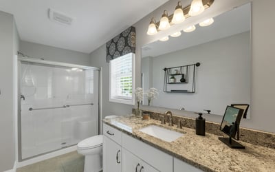 Bright and modern bathroom featuring a spacious countertop, sleek fixtures, and natural light from the window.