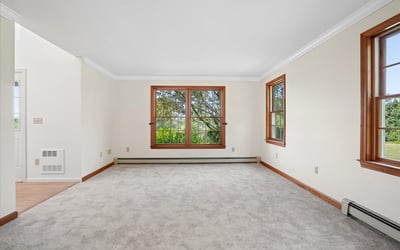 Bright and airy living space featuring large windows and plush carpeting, ideal for personalization and comfort.