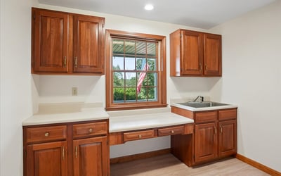 Bright kitchen space featuring ample cabinetry, a large window with outdoor views, and efficient countertop area.