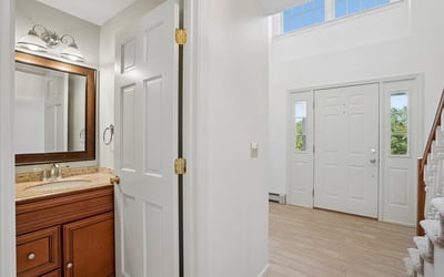 Inviting entryway with dual doors, showcasing bright natural light and a convenient half bath for guests.
