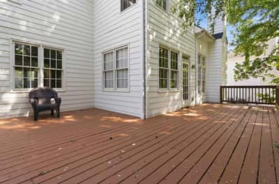 Spacious wood deck perfect for gatherings, surrounded by natural light and nearby greenery.