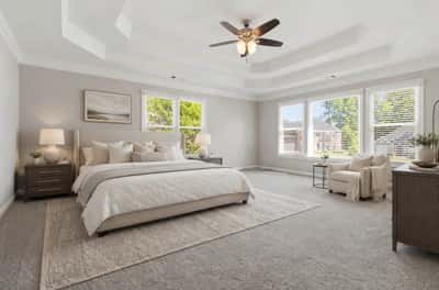 Spacious primary suite featuring high ceilings, abundant natural light, and a cozy reading nook. (Virtual Staging)