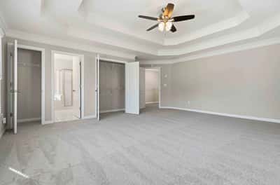 Spacious primary bedroom featuring a coffered ceiling, dual closets, and a bright en-suite bathroom.