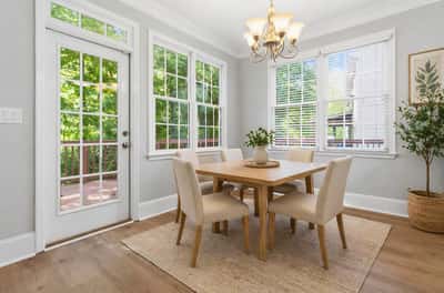 Bright breakfast nook featuring large windows, natural light, and direct access to an outdoor deck. (Virtual Staging)