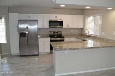 Stylish kitchen with granite countertops, stainless steel appliances, white cabinetry, recessed lighting, and an oversized breakfast bar. This updated Phoenix home offers a modern kitchen designed for both everyday living and entertaining.