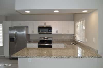 Spacious kitchen overlooking the main living area with granite countertops, recessed lighting, abundant cabinetry, and durable tile flooring. The open floor plan creates an ideal setting for entertaining and daily living.