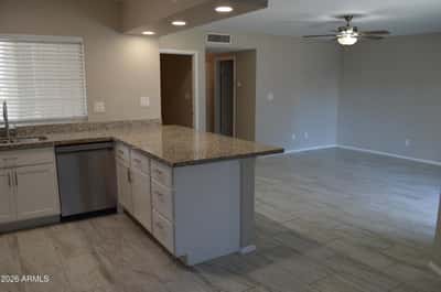 Large granite peninsula anchors this beautifully renovated kitchen with ample workspace, stainless steel appliances, white cabinetry, and contemporary finishes. A perfect blend of style and functionality in Phoenix.