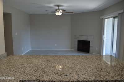 Comfortable living room featuring a modern tiled fireplace, updated flooring, ceiling fan, and sliding glass doors opening to the patio. This inviting space is ideal for everyday living and entertaining.