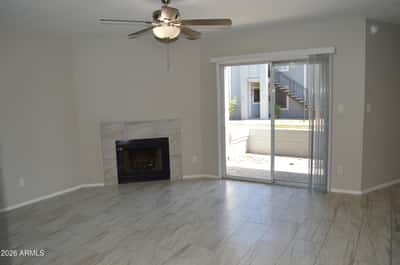 Spacious living area with updated tile flooring, cozy fireplace, ceiling fan, and abundant natural light from the sliding glass doors. The open layout enhances the home's comfortable and move-in-ready appeal.