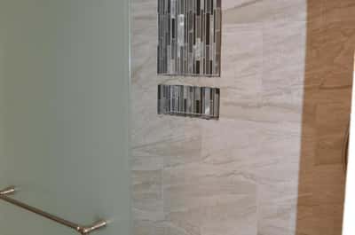 Elegant walk-in shower featuring custom tile, decorative accent niches, and a modern glass enclosure. This beautifully upgraded bathroom showcases craftsmanship and contemporary design.