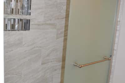 Modern glass-enclosed shower with custom tile walls and decorative insets creates a spa-like atmosphere. Stylish upgrades elevate the appeal of this beautifully renovated Phoenix home.