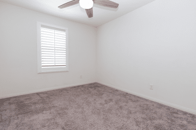 Bright room featuring a ceiling fan and window shutters, perfect for personalizing your private space.