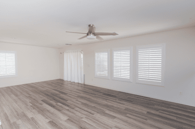 Spacious living area featuring ample natural light and sleek wood-style flooring, perfect for versatile layouts.