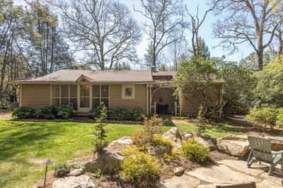 Spacious home nestled among trees, featuring a lush garden and inviting outdoor areas for relaxation.
