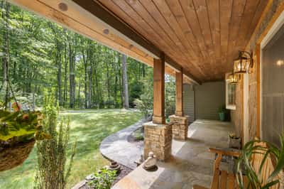 Inviting covered porch overlooking a lush backyard, perfect for relaxing and enjoying nature’s beauty.