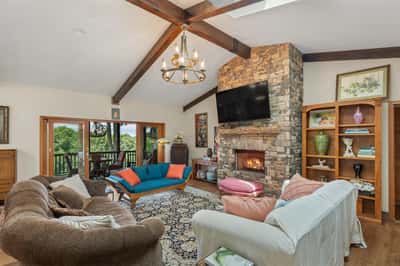 Spacious living area features a stunning stone fireplace and expansive windows overlooking picturesque landscapes.